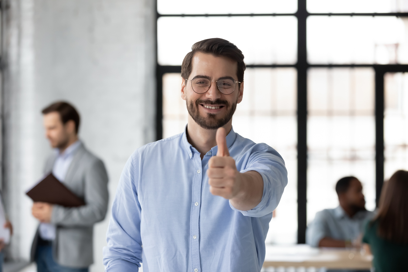 Satisfied loyal male client posing in office raising thumb up